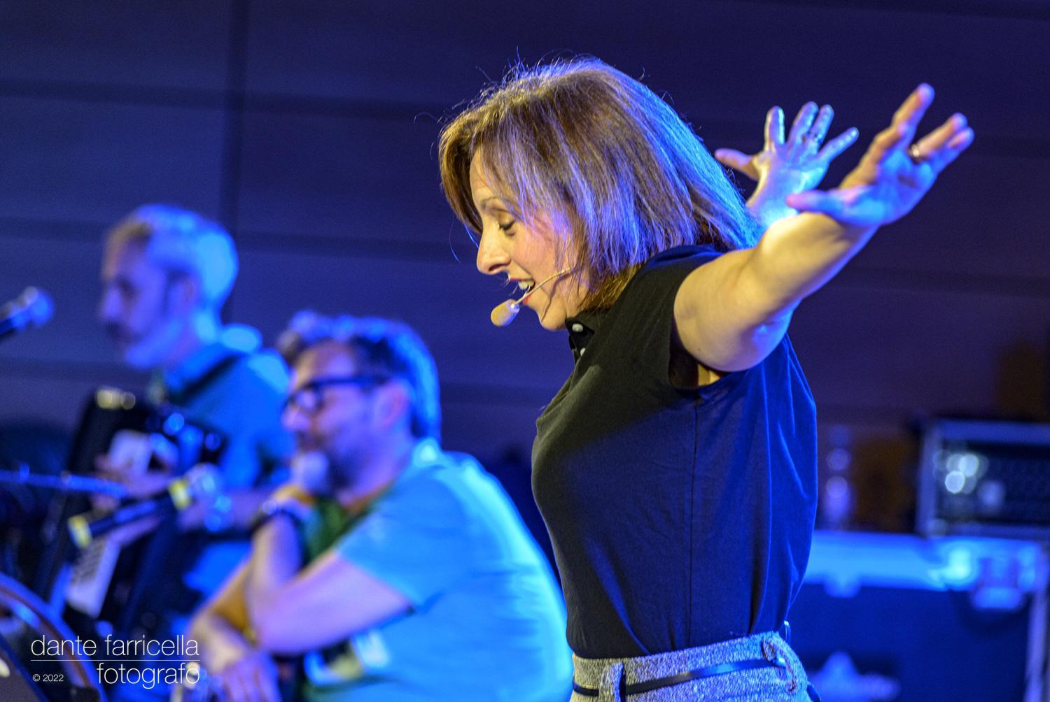 Maria Giulia Campioli a braccia aperte, con Francesco Grillenzoni e Stefano Garuti che suonano sullo sfondo.